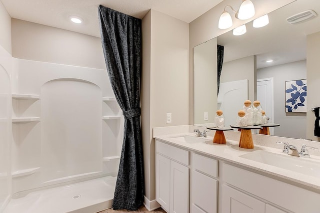 full bathroom with a sink, visible vents, a shower, and double vanity