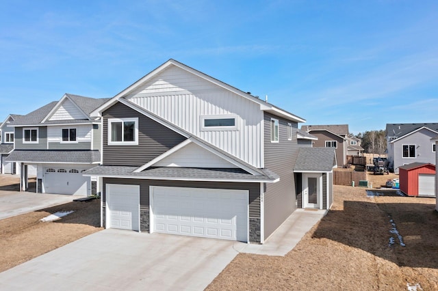 townhome / multi-family property with stone siding, driveway, a shingled roof, and a garage