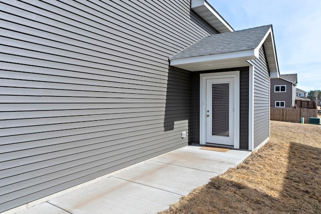 property entrance featuring fence and a shingled roof