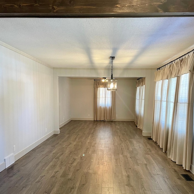 unfurnished dining area featuring plenty of natural light, visible vents, and wood finished floors