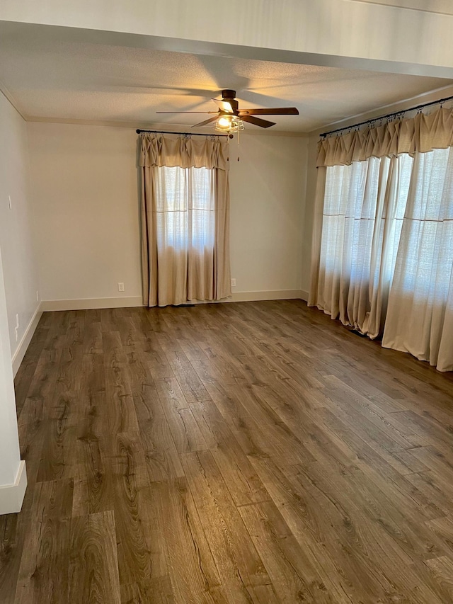 unfurnished room featuring ceiling fan, a textured ceiling, baseboards, and dark wood-type flooring