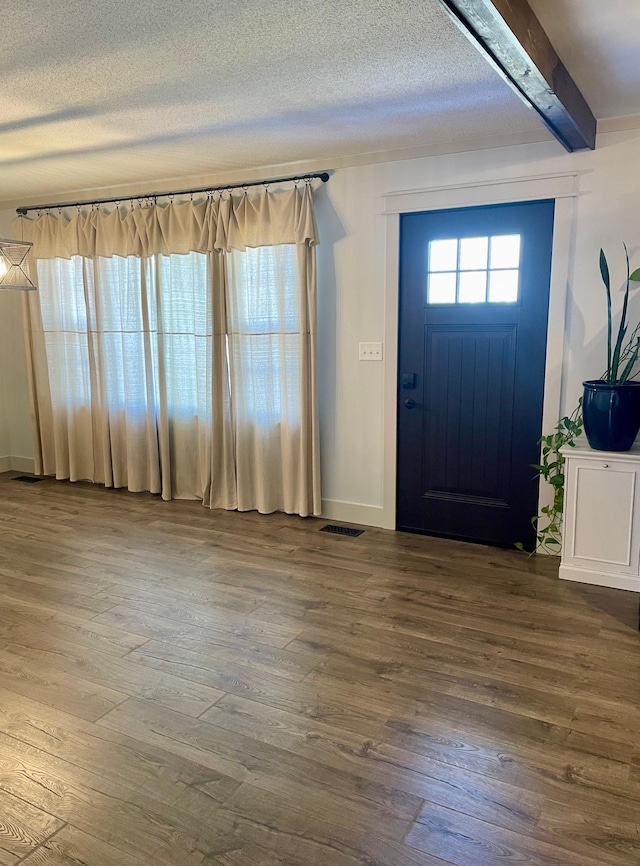 entryway with a textured ceiling, wood finished floors, and visible vents