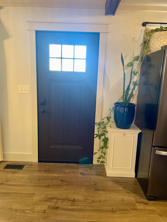 entrance foyer with beamed ceiling, wood finished floors, and visible vents