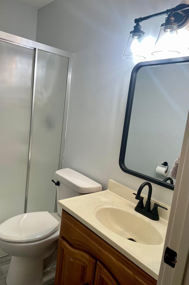 bathroom with a stall shower, vanity, and toilet