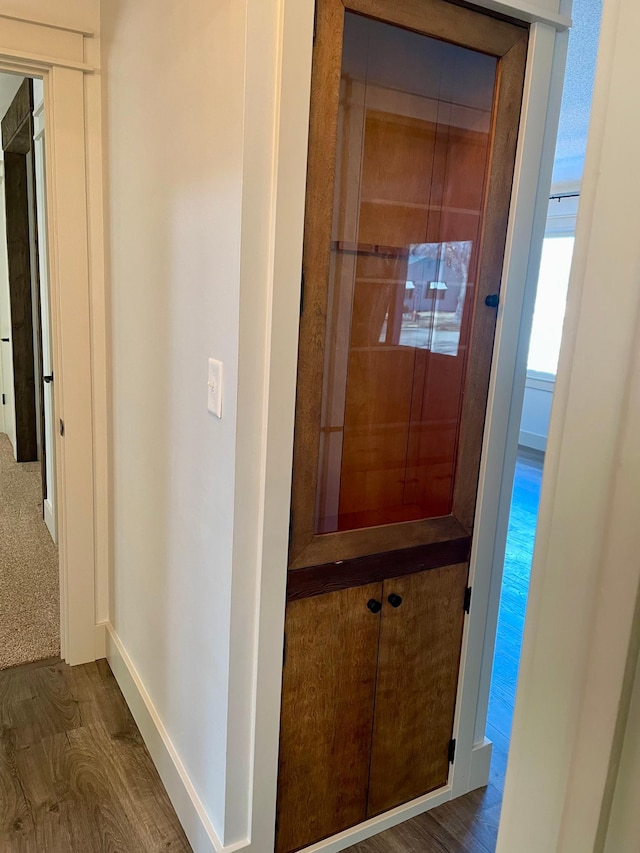 corridor with baseboards and wood finished floors