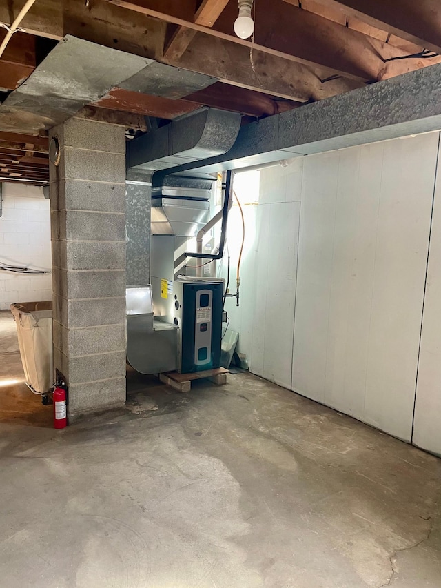 unfinished basement with concrete block wall and heating unit