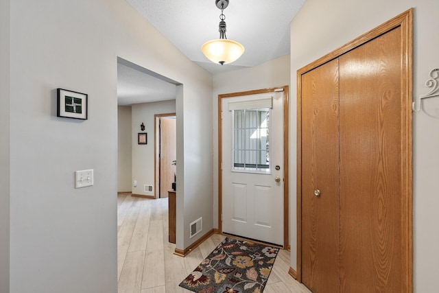 foyer featuring baseboards, visible vents, and light wood-type flooring