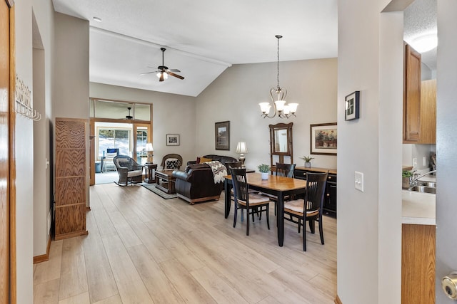 dining space featuring ceiling fan with notable chandelier, high vaulted ceiling, and light wood-type flooring