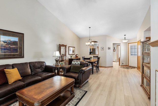 living area featuring light wood finished floors, a notable chandelier, high vaulted ceiling, and baseboards