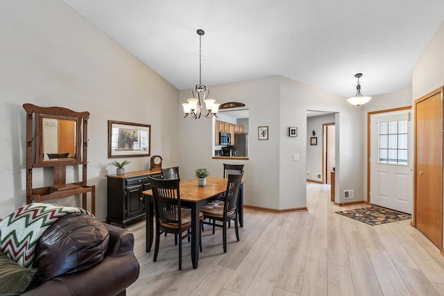 dining space with visible vents, baseboards, a chandelier, light wood-type flooring, and lofted ceiling