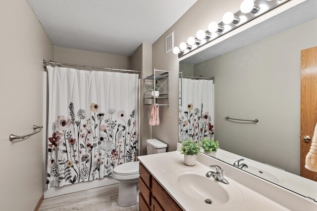 bathroom with visible vents, toilet, vanity, a shower with curtain, and a textured ceiling