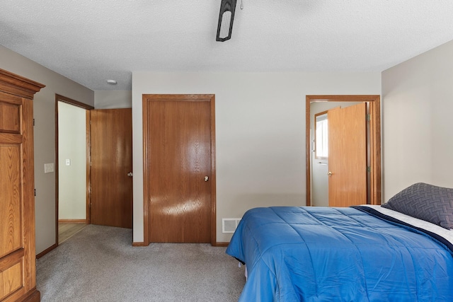 carpeted bedroom with a closet, visible vents, a textured ceiling, and baseboards