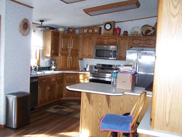 kitchen featuring wallpapered walls, stainless steel appliances, a textured ceiling, and a sink