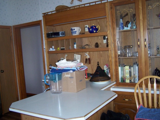 kitchen with brown cabinets, wallpapered walls, and light countertops