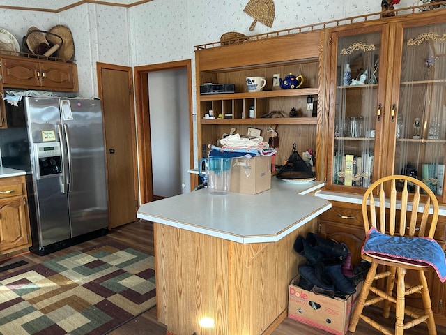 kitchen featuring brown cabinets, wallpapered walls, a peninsula, stainless steel fridge with ice dispenser, and light countertops