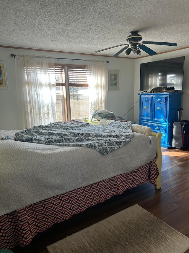 bedroom featuring multiple windows, a textured ceiling, a ceiling fan, and wood finished floors