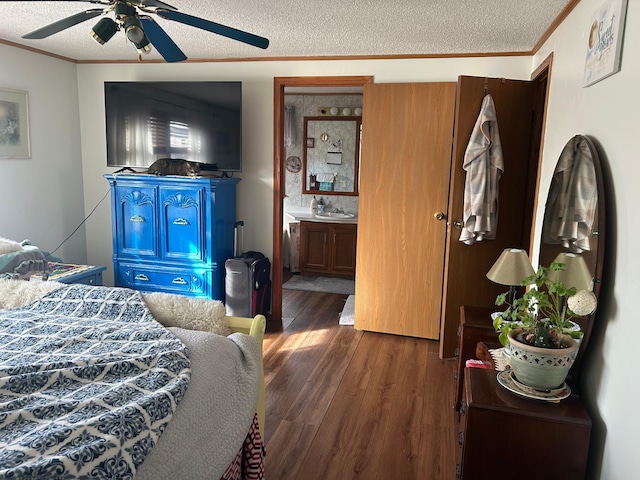 bedroom featuring dark wood finished floors, ornamental molding, ensuite bath, a textured ceiling, and a sink