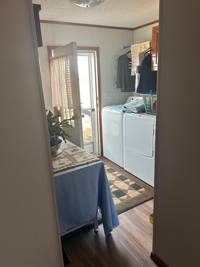 laundry area featuring wood finished floors, a textured ceiling, washing machine and dryer, and ornamental molding