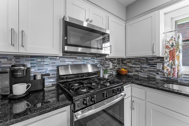 607 Adams St NE, Minneapolis, MN 55413 - kitchen featuring appliances with stainless steel finishes, white cabinets, backsplash, dark stone countertops, and a sink