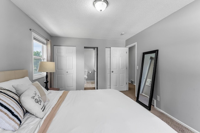 607 Adams St NE, Minneapolis, MN 55413 - bedroom with a textured ceiling, baseboards, carpet floors, two closets, and connected bathroom