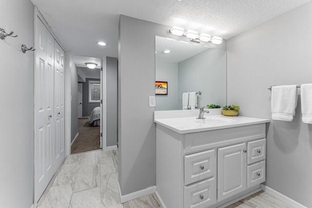 607 Adams St NE, Minneapolis, MN 55413 - ensuite bathroom with vanity, marble look tiles, baseboards, a textured ceiling, and recessed lighting