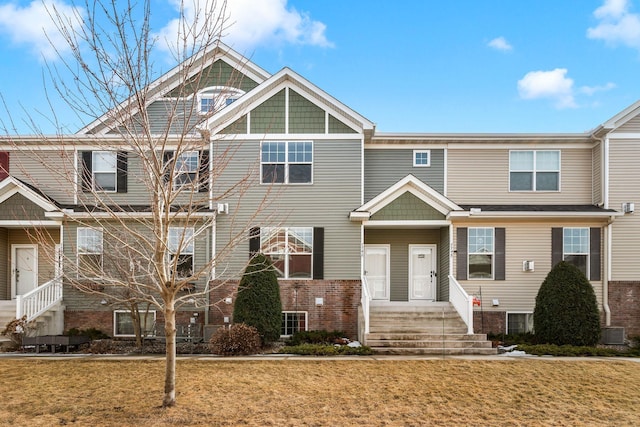 multi unit property featuring brick siding, central AC unit, and a front yard