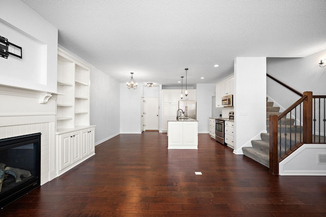 living area featuring stairway, a textured ceiling, dark wood-style floors, and a fireplace