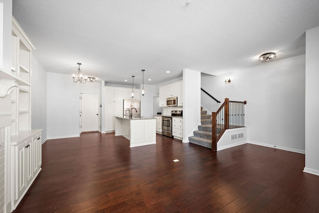 unfurnished living room featuring stairway, dark wood-style floors, visible vents, baseboards, and an inviting chandelier