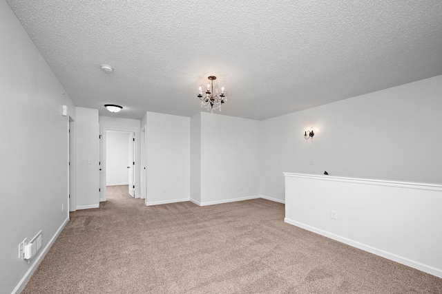 carpeted empty room with an inviting chandelier, visible vents, baseboards, and a textured ceiling