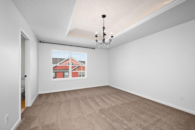 spare room with a raised ceiling, a textured ceiling, carpet floors, baseboards, and a chandelier