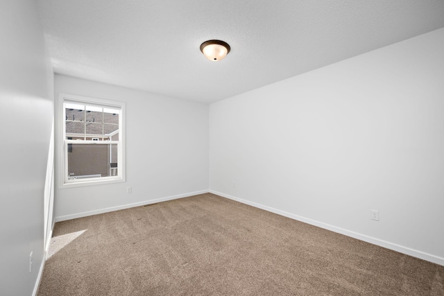 carpeted empty room featuring baseboards