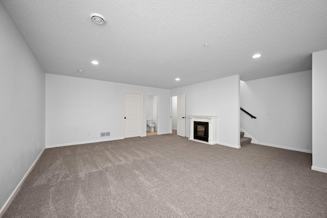 unfurnished living room with visible vents, baseboards, stairway, recessed lighting, and a glass covered fireplace