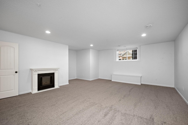 unfurnished living room with baseboards, carpet flooring, recessed lighting, a fireplace, and a textured ceiling