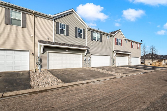 townhome / multi-family property featuring a residential view, driveway, and a garage