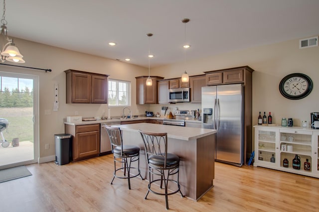 kitchen featuring a sink, visible vents, a kitchen breakfast bar, appliances with stainless steel finishes, and light wood-type flooring