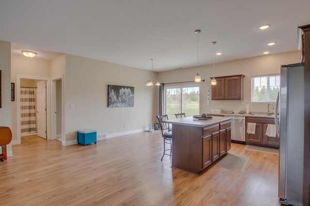 kitchen featuring a breakfast bar, stainless steel appliances, a wealth of natural light, and a center island