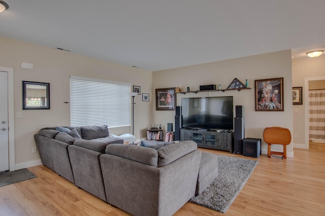 living area featuring visible vents, light wood-style flooring, and baseboards