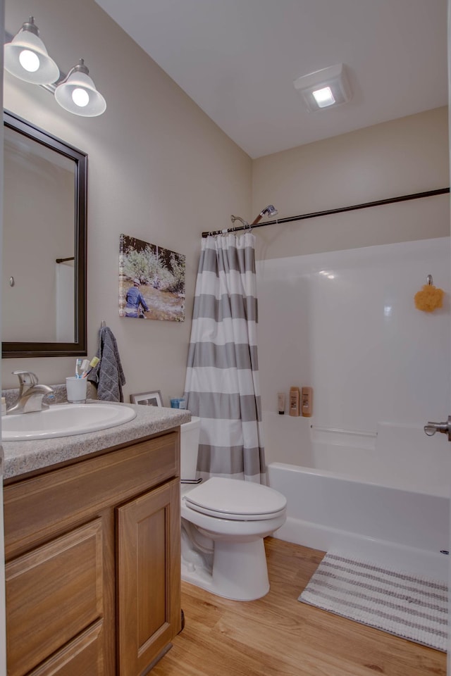 full bath with shower / bath combo, vanity, toilet, and wood finished floors