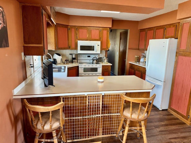 1001 1st Ave NW, Pelican Rapids, MN 56572 - kitchen featuring white appliances, a peninsula, light countertops, dark wood finished floors, and brown cabinetry
