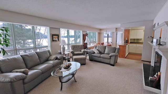 living room with light carpet, a textured ceiling, and a glass covered fireplace