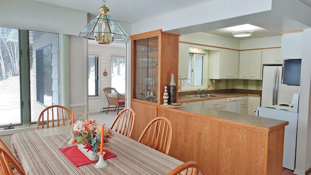 kitchen with white appliances, a textured ceiling, a baseboard heating unit, pendant lighting, and a sink