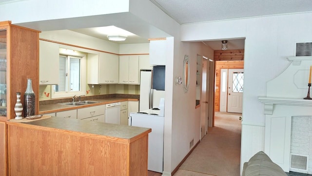 kitchen with white cabinetry, a sink, a textured ceiling, white appliances, and a peninsula