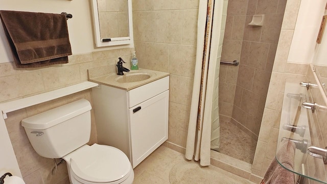 bathroom with toilet, a stall shower, tile walls, and vanity