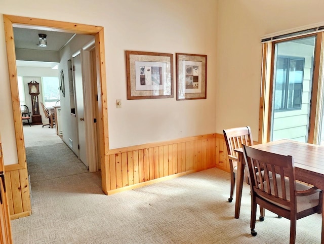 dining area featuring light colored carpet, wainscoting, and wooden walls