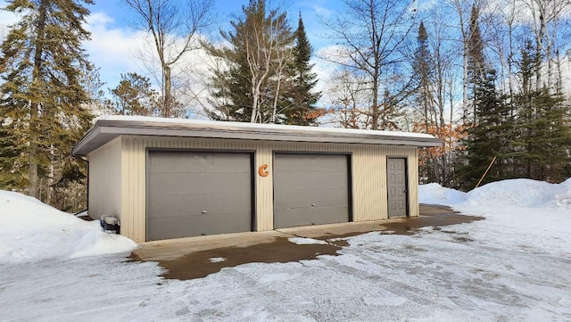 snow covered garage featuring a detached garage