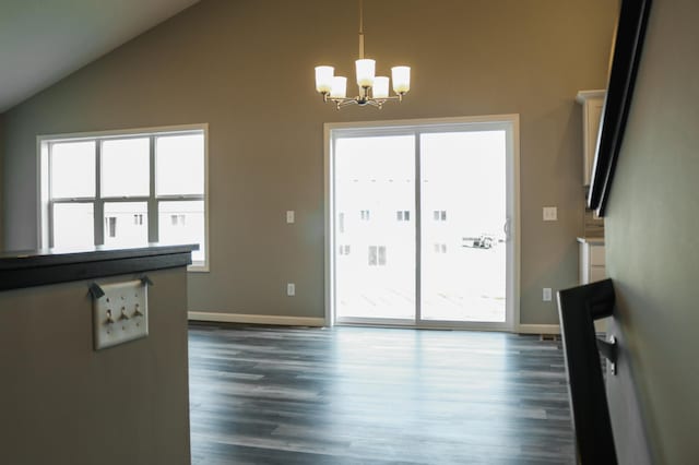 unfurnished living room featuring a notable chandelier, a healthy amount of sunlight, and lofted ceiling