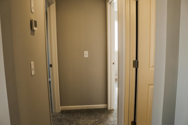 hall with baseboards and dark colored carpet