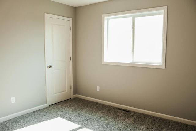 unfurnished room with carpet flooring, visible vents, and baseboards