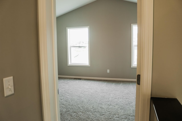 carpeted spare room with a healthy amount of sunlight, baseboards, and vaulted ceiling