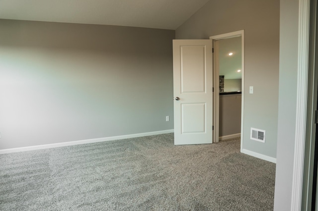 carpeted spare room with visible vents, baseboards, and vaulted ceiling